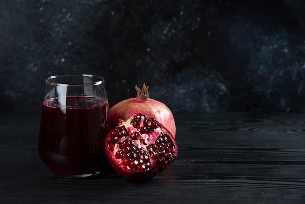 Photo gratuite une tasse en verre de jus de grenade à l'obscurité.