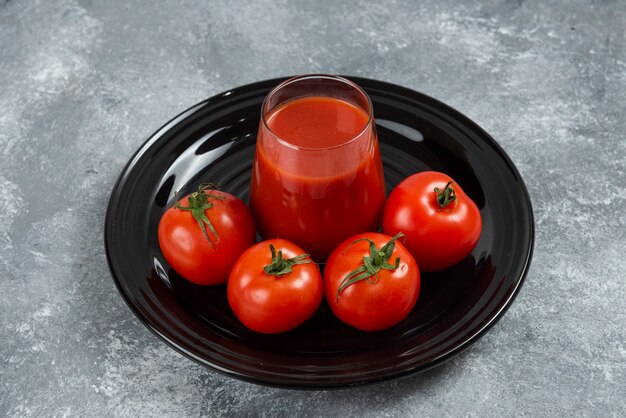 Une tasse en verre de jus de tomate sur une plaque noire.