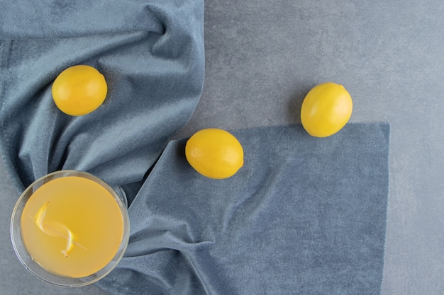 Une tasse en verre de limonade avec des citrons entiers