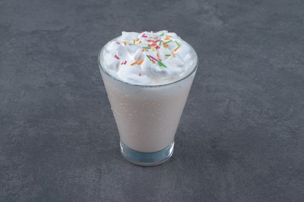 Une tasse en verre de milkshake sucré avec de la crème fouettée.