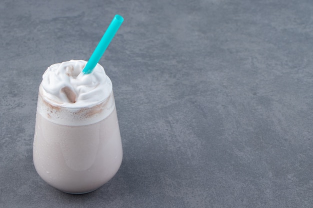 Une tasse en verre de milkshake sucré avec de la crème fouettée