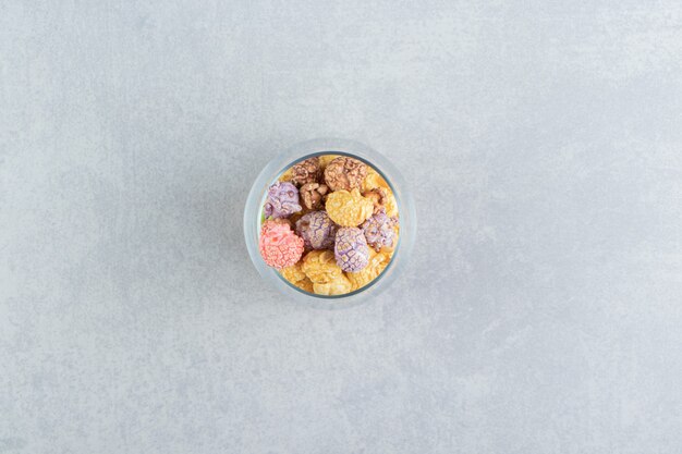 Une tasse en verre pleine de pop-corn multicolore sucré.