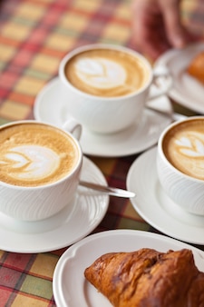 Tasses de café cappuccino avec croissant dans un café
