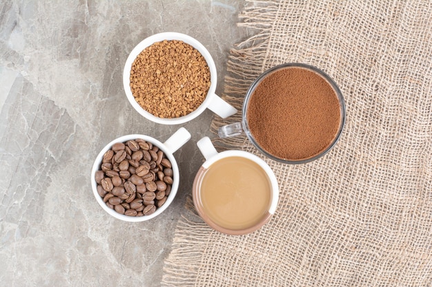 Tasses de café, grains de café et café moulu sur une surface en marbre. photo de haute qualité