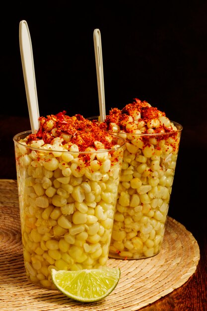 Des tasses avec de délicieuses esquites et du citron vert