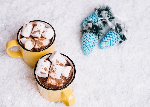 Photo gratuite tasses avec des guimauves près de jouets de noël entre neige