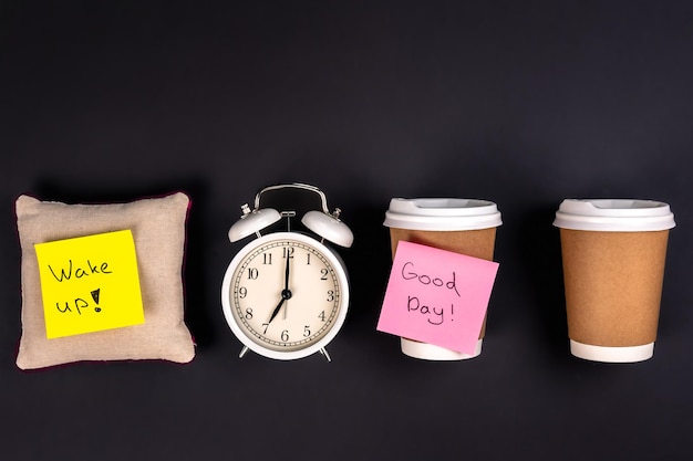 Photo gratuite tasses jetables blanches de réveil et un petit oreiller sur un fond foncé