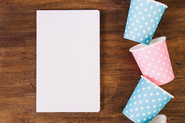 Tasses en papier près de cahier blanc