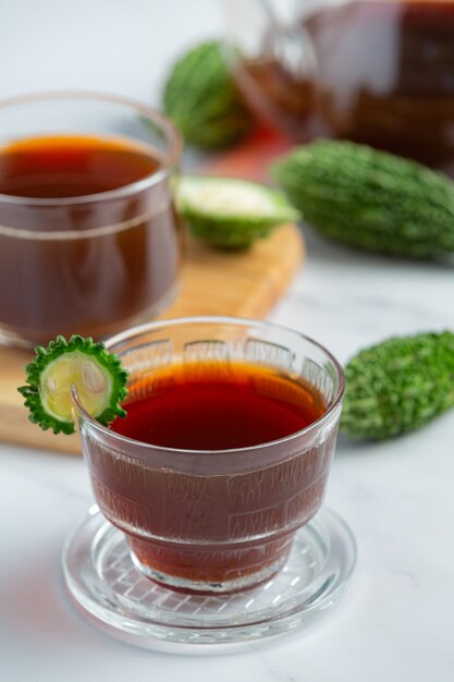 Tasses de thé de gourde amère chaud avec gourde amère en tranches crues sur sol en marbre blanc