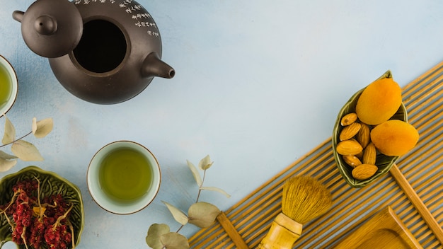 Photo gratuite tasses à thé traditionnelles brunes avec feuilles et fruits secs sur fond blanc