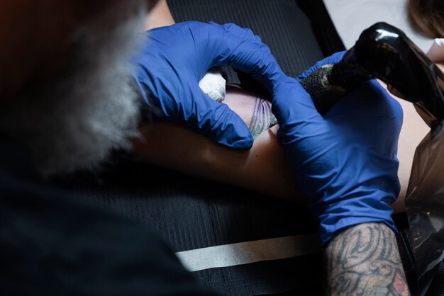 Tatoueur expérimenté travaillant sur le tatouage du client