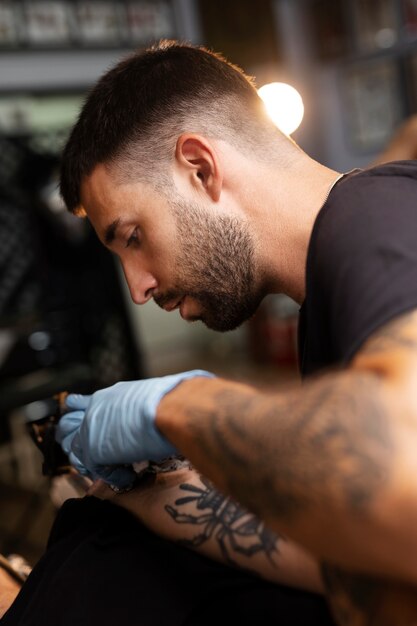 Tatoueur de vue de côté faisant son travail