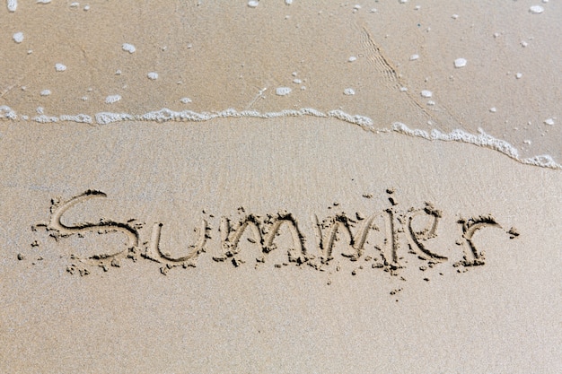 Été inscription manuscrite dans le sable sur une plage