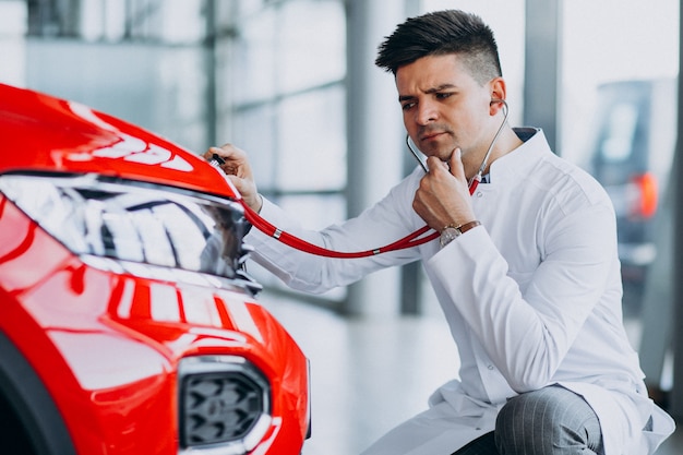 Photo gratuite technicien automobile avec stéthoscope dans un showroom automobile