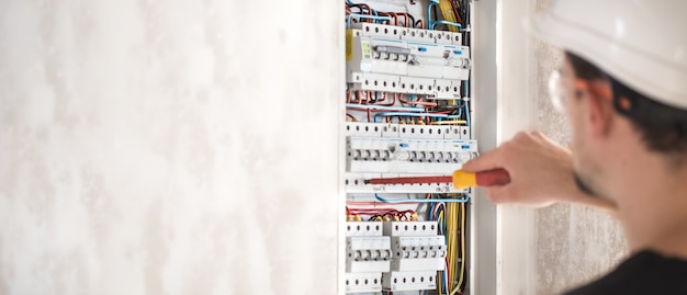 Un technicien électricien travaillant dans un tableau avec fusibles