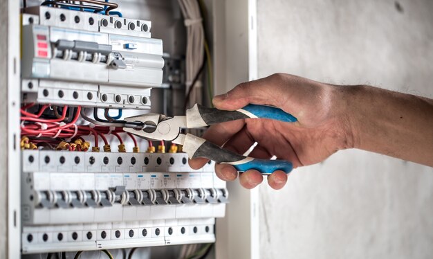 Un technicien électricien travaillant dans un tableau avec fusibles