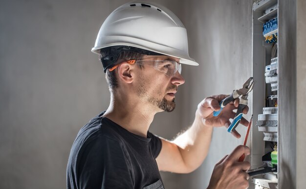 Un technicien électricien travaillant dans un tableau avec fusibles