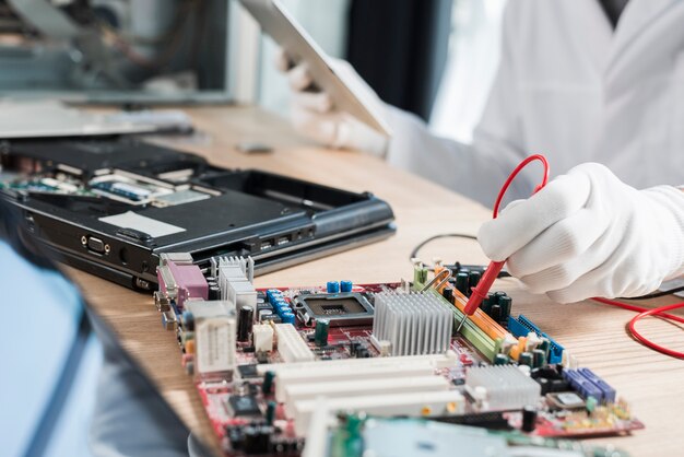 Un technicien examine une carte mère avec un multimètre numérique