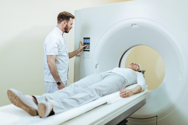 Technicien médical et patient mature pendant la procédure d'examen IRM à la clinique