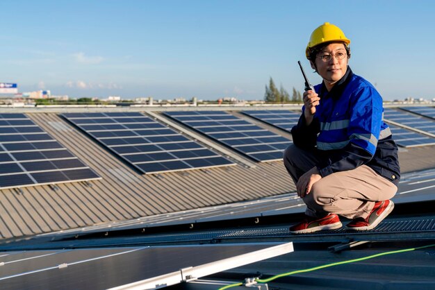 Technicien spécialisé ingénieur professionnel avec ordinateur portable et tablette vérifiant l'entretien de l'installation d'un panneau de toit solaire sur le toit de l'usine sous la lumière du soleil Ingénieurs tenant une tablette vérifiant le toit solaire