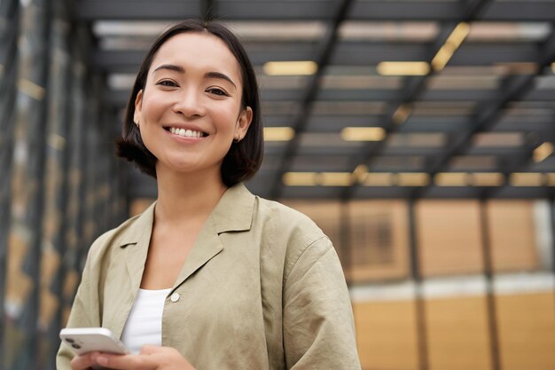 Technologie et personnes souriantes fille asiatique avec téléphone portable utilisant le téléphone et marchant dans la ville de da