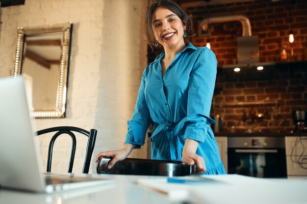 Technologie, profession et concept de travail à distance. Confiant jeune rédacteur féminin debout dans la cuisine