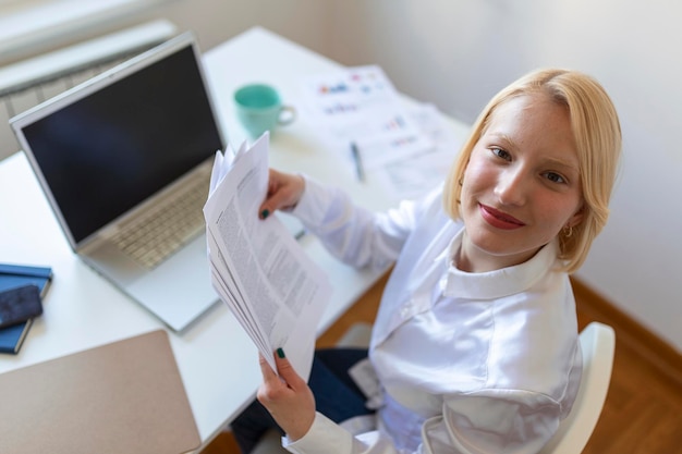 Technologie de travail à distance et concept de personnes heureuse souriante jeune femme d'affaires avec ordinateur portable et papiers travaillant au bureau à domicile pendant la crise sanitaire de Covid19