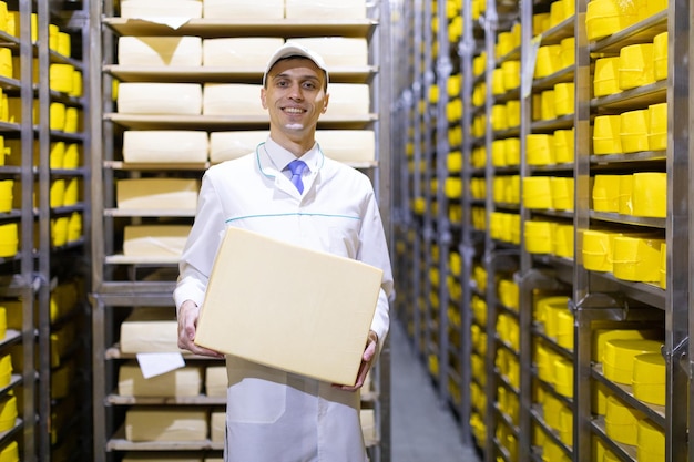 Un technologue avec du fromage dans les mains effectue une inspection de la production prête au département de l'usine laitière