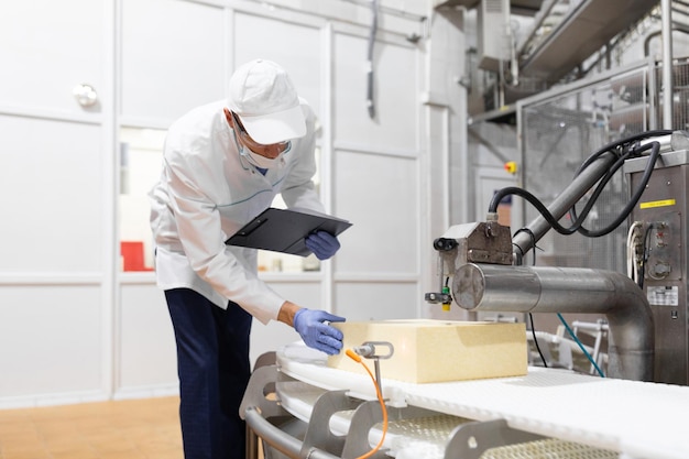 Un technologue prépare la chaîne de production tout en se tenant près d'un écran numérique au département de l'usine laitière