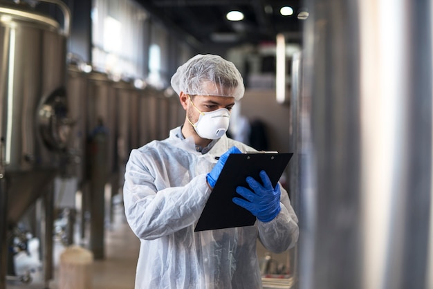 Technologue en uniforme blanc contrôle de la qualité dans l'usine de production industrielle