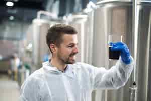 Photo gratuite technologue vérifiant la qualité du produit dans l'usine de production d'alcool de boisson