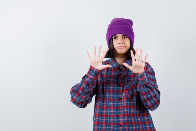 Teen femme en chemise à carreaux et bonnet gesticulant isolé