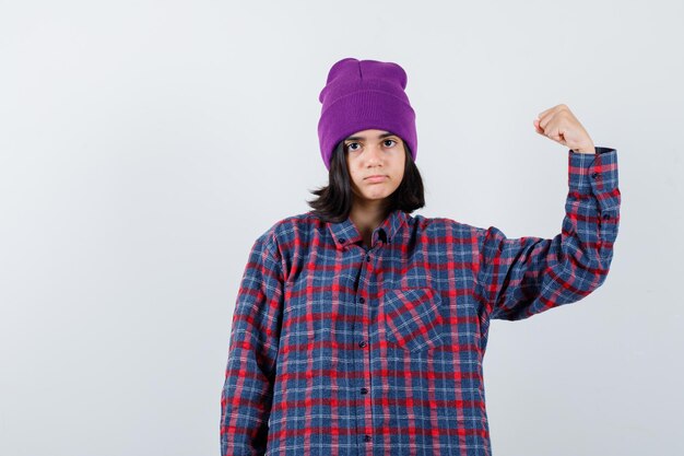 Teen femme en chemise à carreaux et bonnet gesticulant isolé