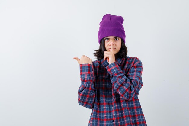 Teen femme en chemise à carreaux et bonnet gesticulant isolé