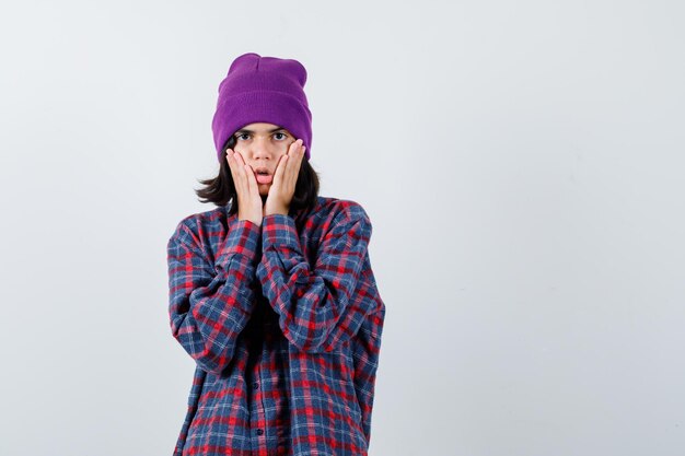 Teen femme en chemise à carreaux et bonnet gesticulant isolé