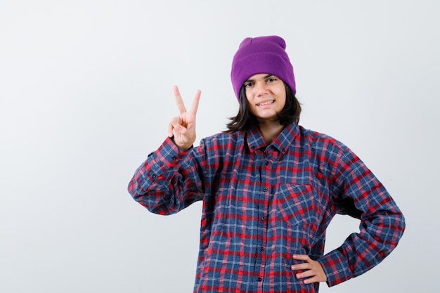 Teen femme en chemise à carreaux et bonnet gesticulant isolé