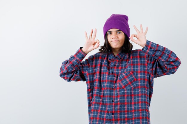 Teen femme en chemise à carreaux et bonnet gesticulant isolé