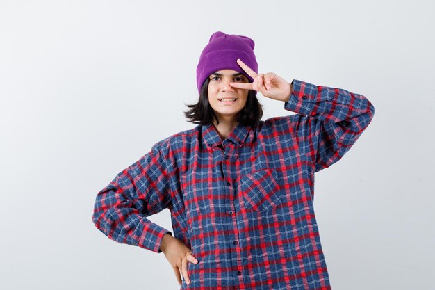 Teen femme en chemise à carreaux et bonnet gesticulant isolé