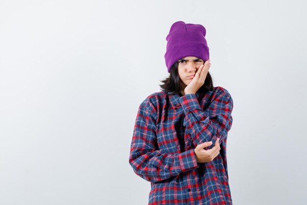 Teen femme en chemise à carreaux et bonnet gesticulant isolé