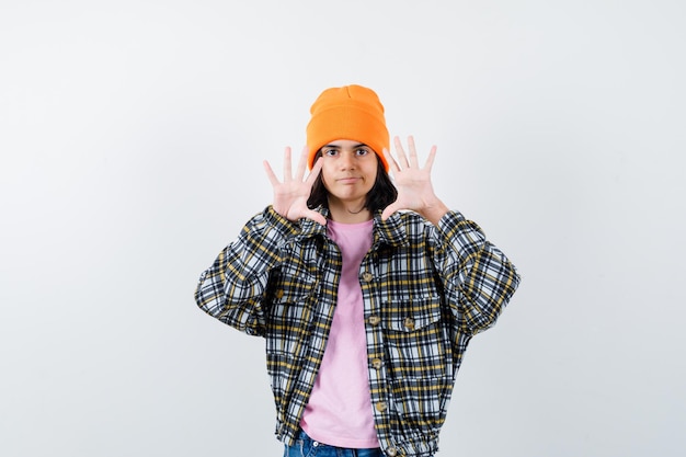 Teen femme en chemise à carreaux et bonnet gesticulant isolé