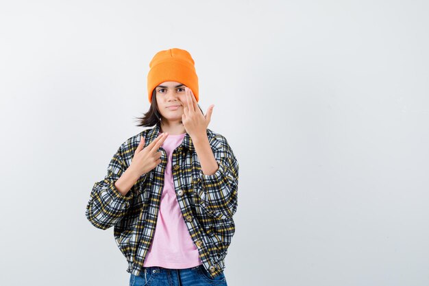 Teen femme en chemise à carreaux et bonnet gesticulant isolé