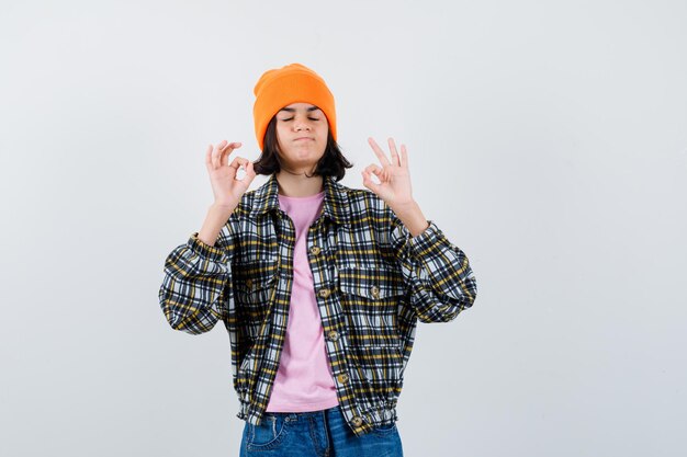 Teen femme en chemise à carreaux et bonnet gesticulant isolé