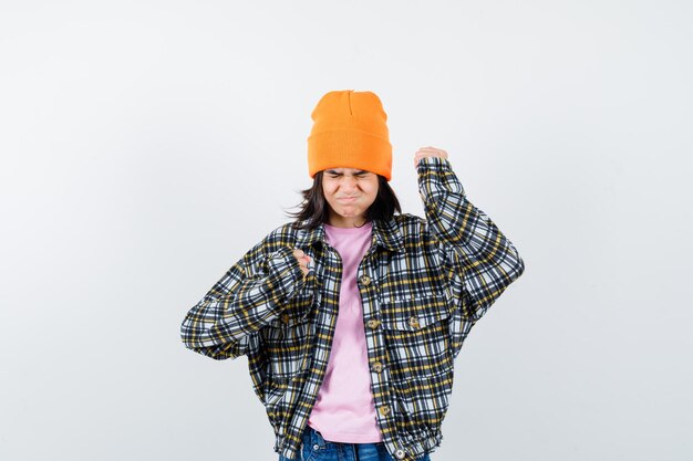 Teen femme en chemise à carreaux et bonnet gesticulant isolé