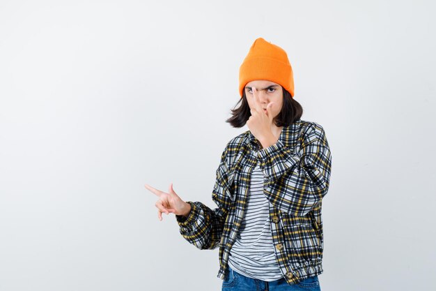 Teen femme en chemise à carreaux et bonnet gesticulant isolé