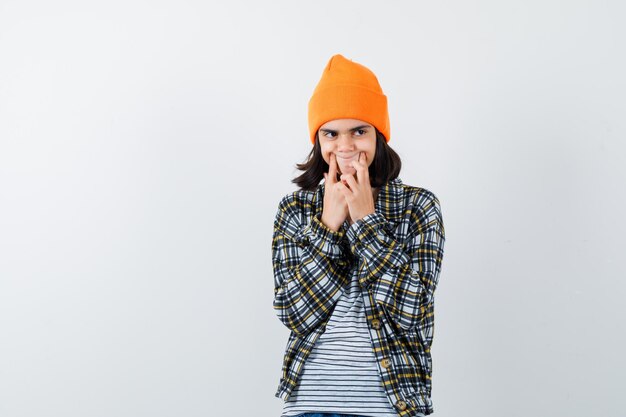 Teen femme en chemise à carreaux et bonnet gesticulant isolé