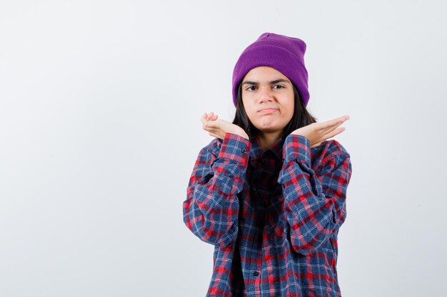 Teen femme en chemise à carreaux et bonnet gesticulant isolé