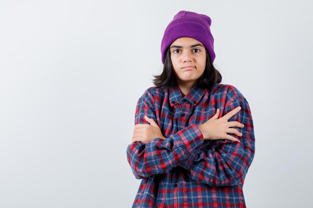 Teen femme en chemise à carreaux et bonnet gesticulant isolé