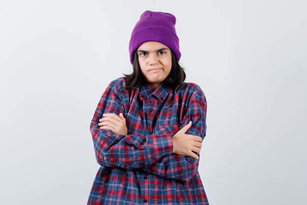 Teen femme en chemise à carreaux et bonnet gesticulant isolé