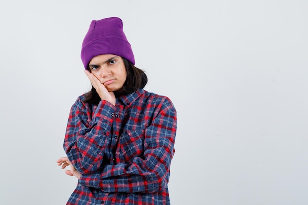 Teen femme en chemise à carreaux et bonnet gesticulant isolé