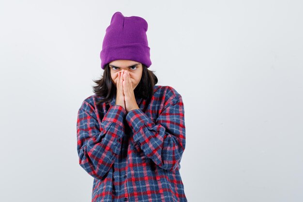 Teen femme en chemise à carreaux et bonnet gesticulant isolé